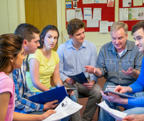 Photo of group of individuals doing group work outdoors in a wooded area